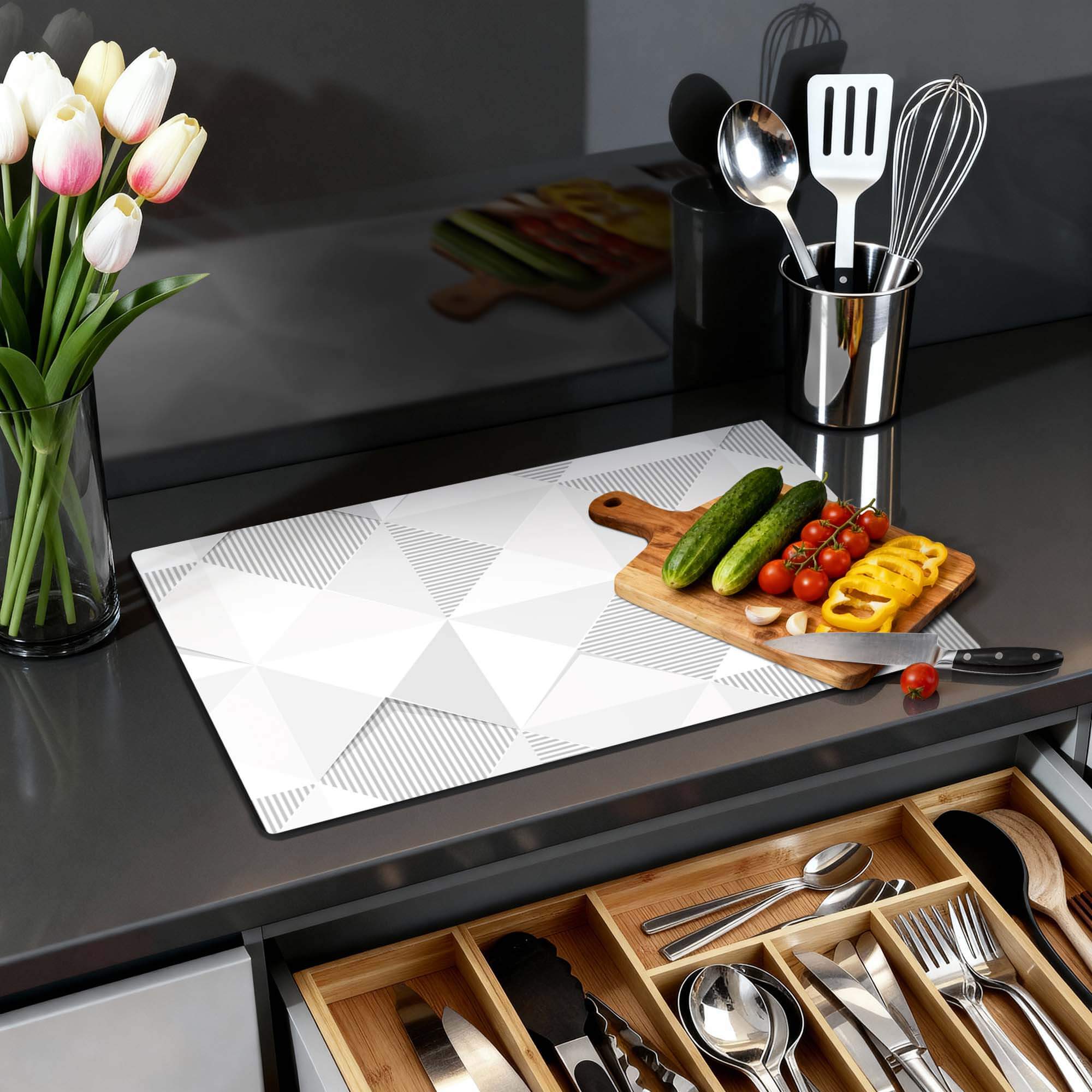 Arctic Prism - Herdabdeckplatte auf einer Küchenarbeitsplatte mit Gemüse und Blumen in einer modernen Küche.