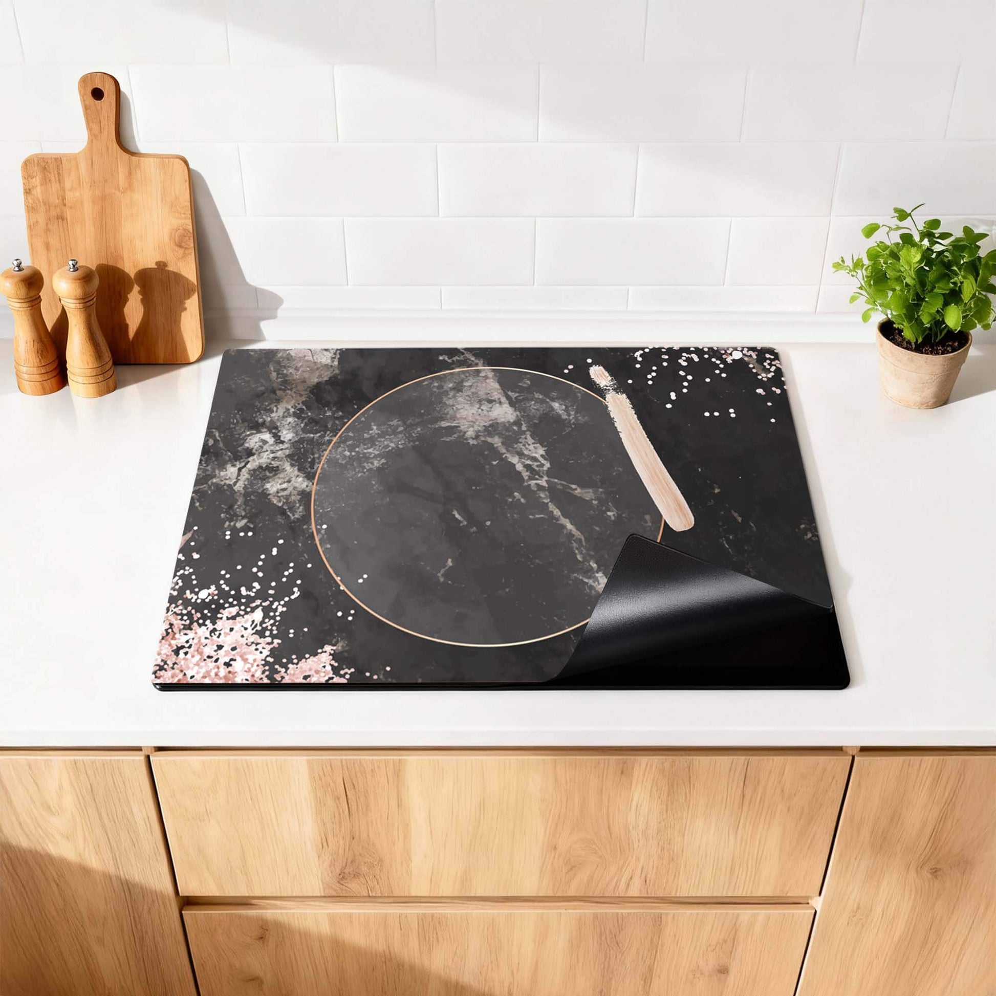 Midnight Rose - Herdabdeckplatte mit schwarzem Marmor und roségoldenen Details auf einer Küchenarbeitsplatte.