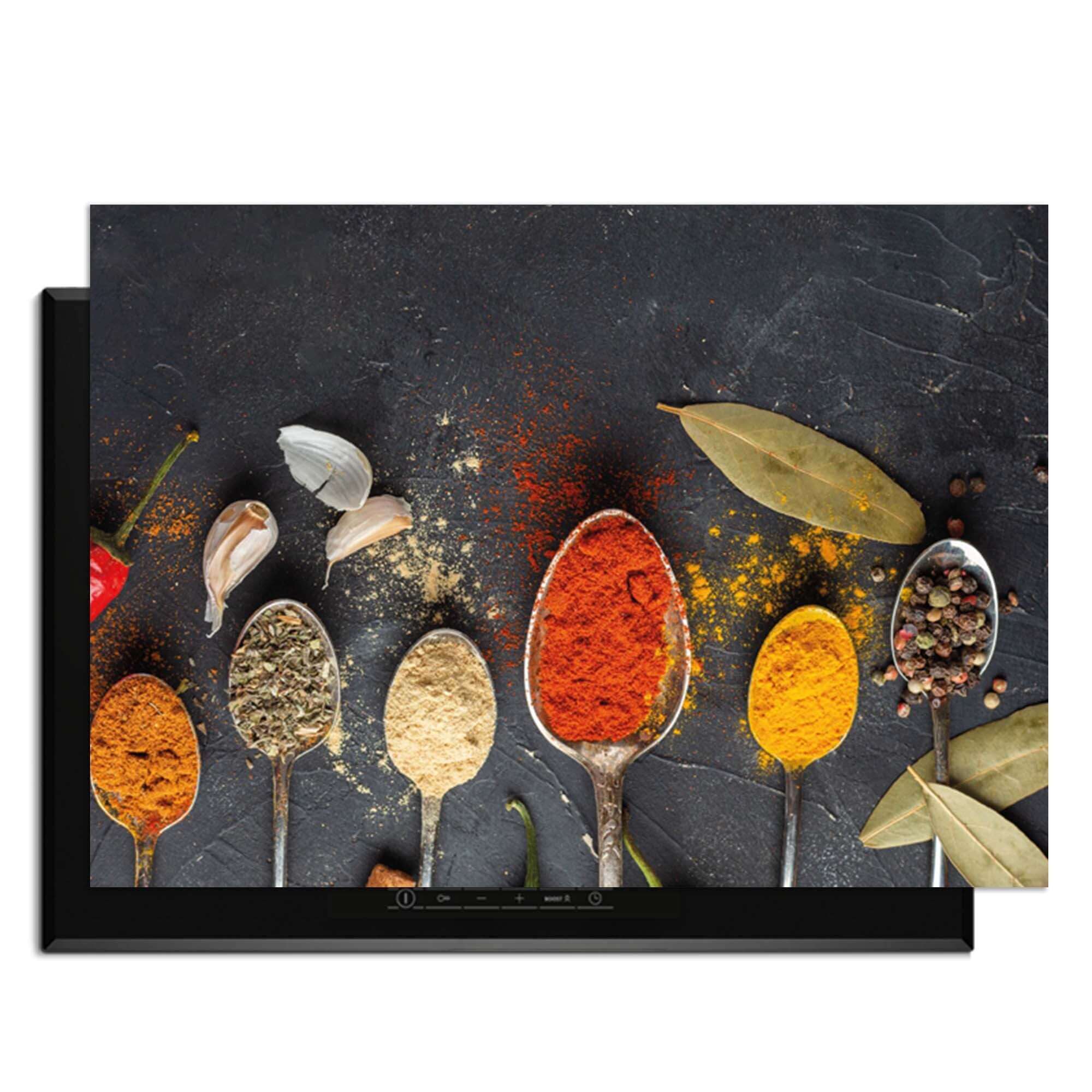 Spice Essence - Herdabdeckplatte mit Löffeln voller Gewürze auf einem dunklen Hintergrund.
