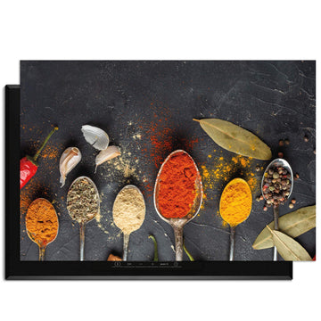 Spice Essence - Herdabdeckplatte mit Löffeln voller Kräuter und Gewürze auf dunklem Hintergrund.