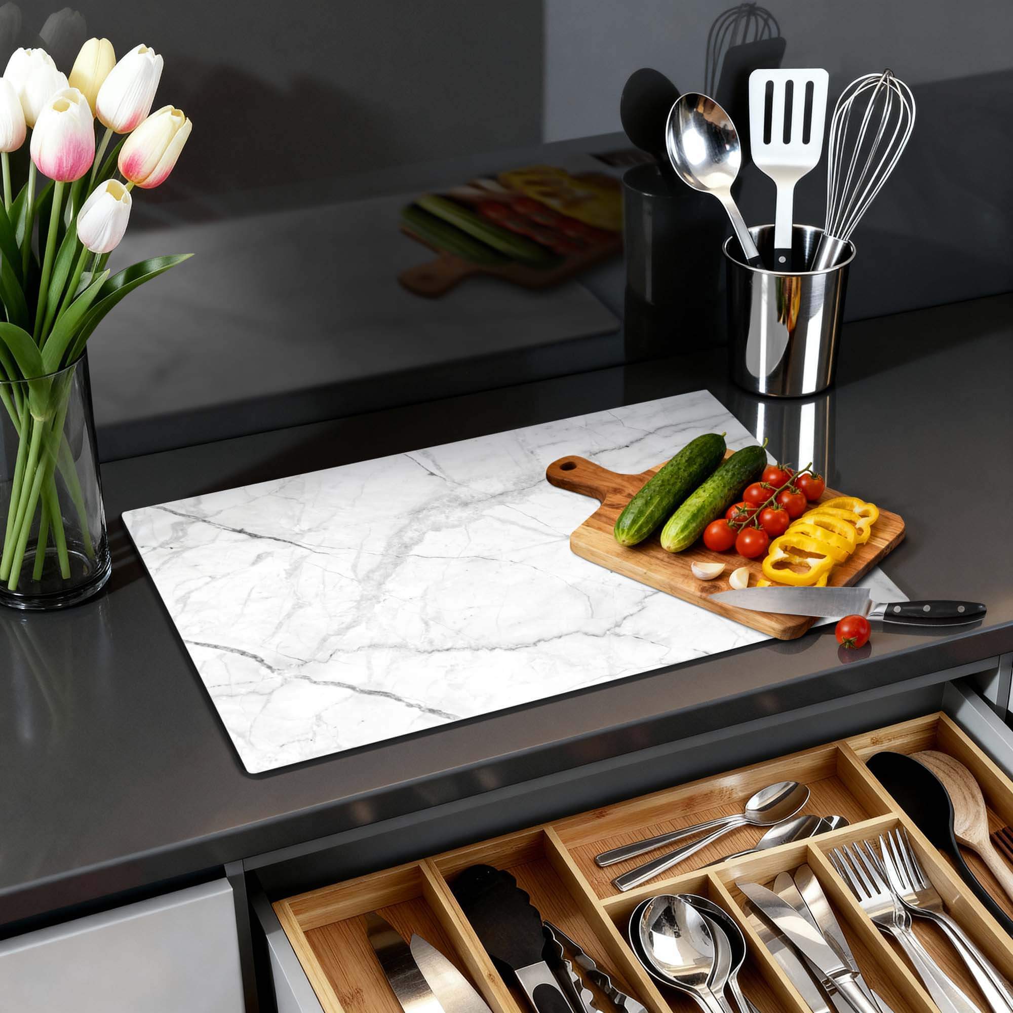 Carrara Light - Herdabdeckplatte auf einer Küchenarbeitsplatte mit Gemüse und Blumen.