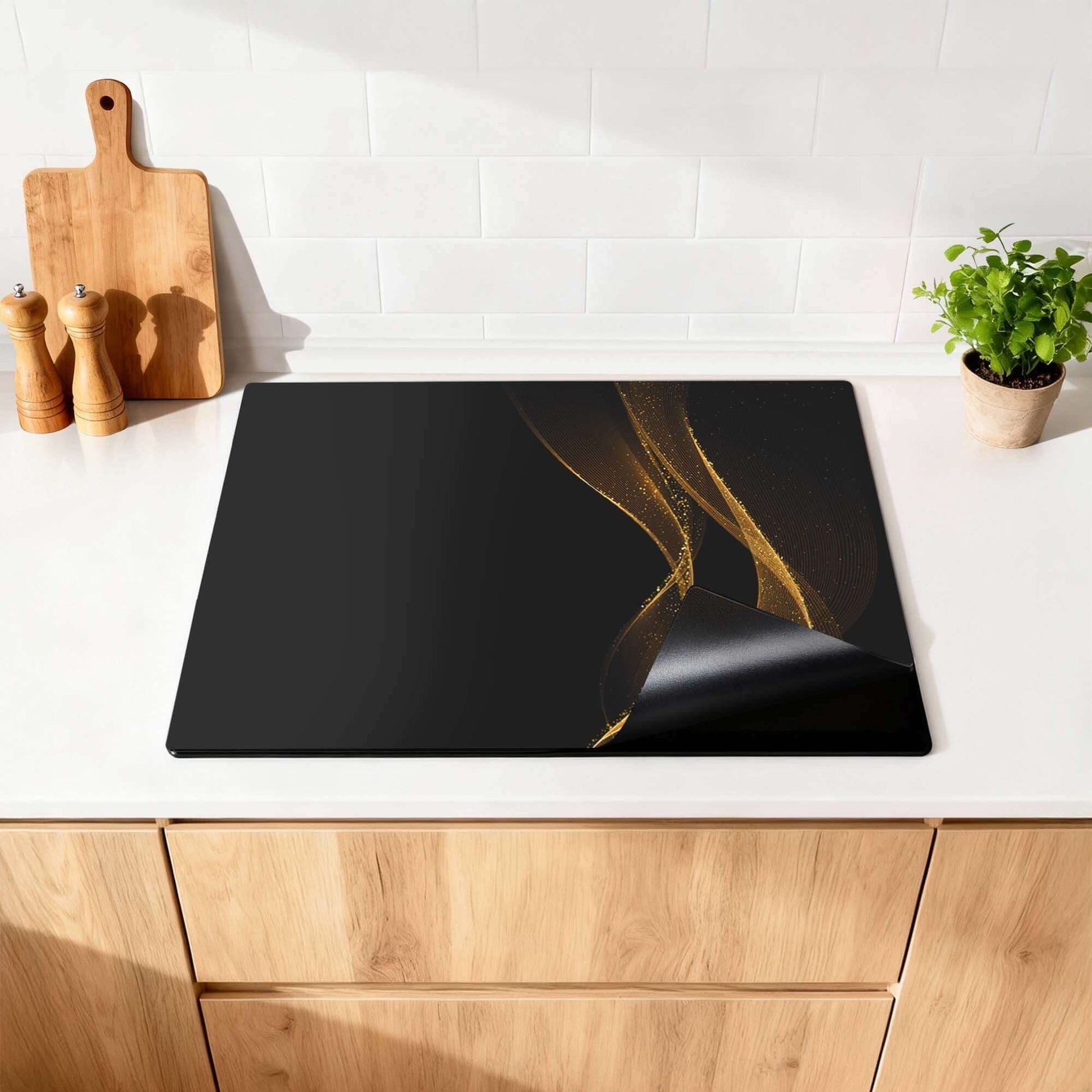 Golden Flow - Herdabdeckplatte auf einer Küchenplatte mit Golddruck auf Schwarz.