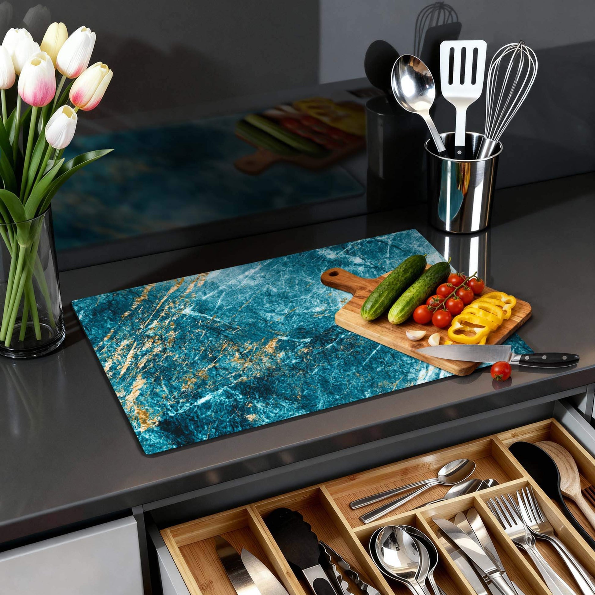 Deep Ocean Marble - Herdabdeckplatte auf einer modernen Küchenarbeitsplatte mit Gemüse und Blumen.