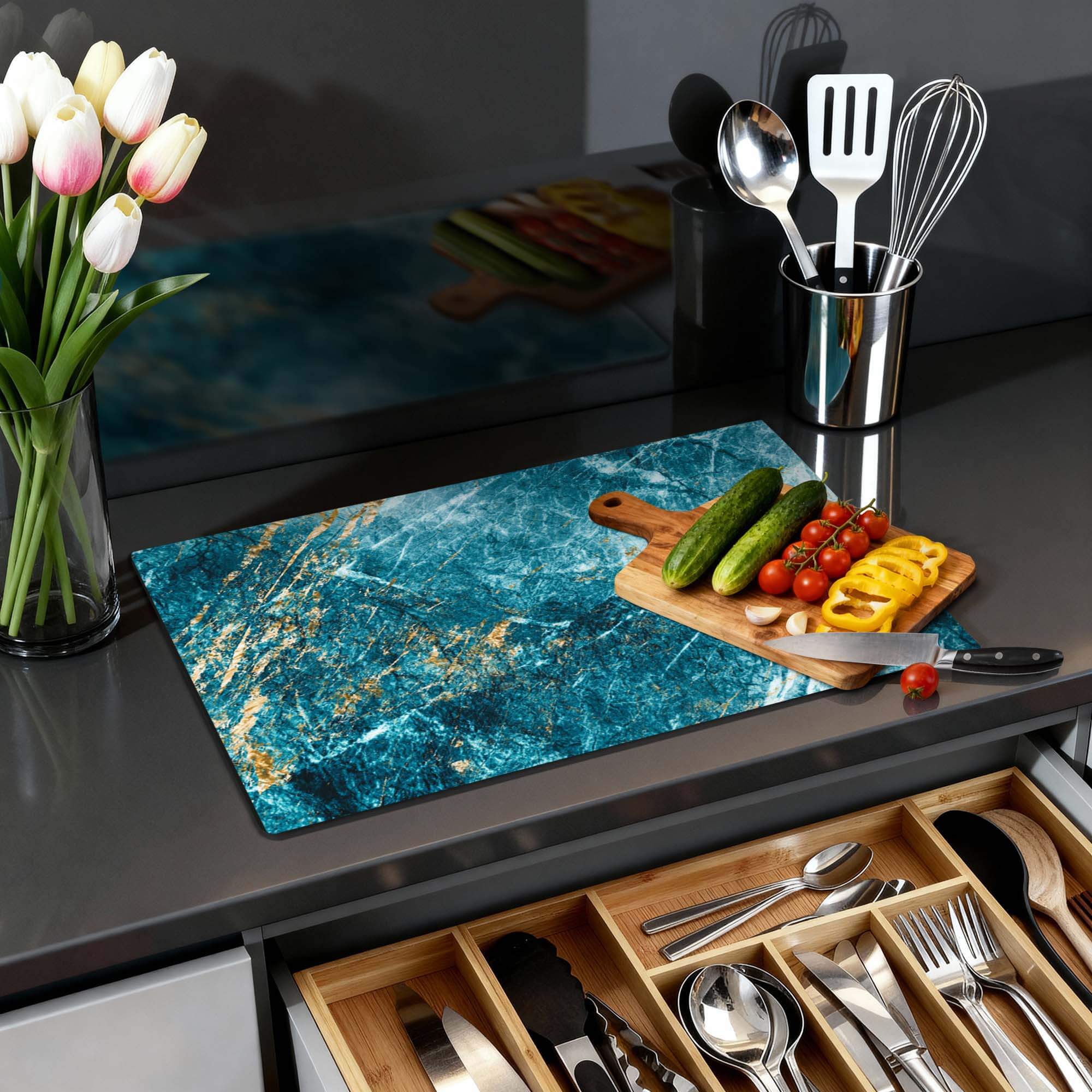 Deep Ocean Marble - Herdabdeckplatte auf einer modernen Küchenarbeitsplatte mit Gemüse und Blumen.