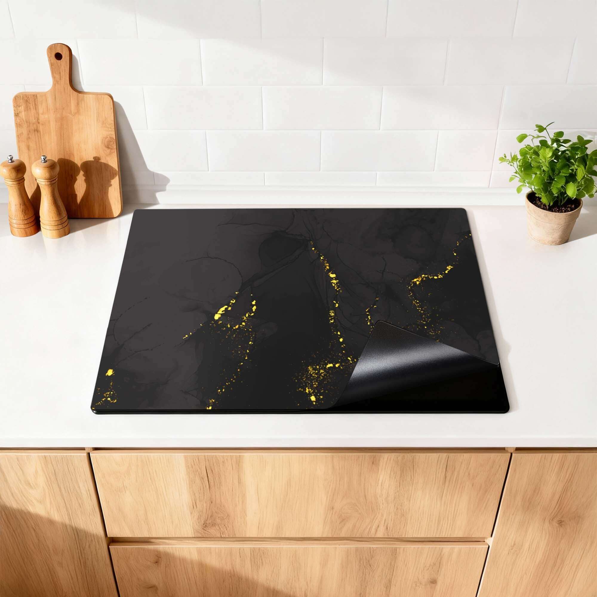 Black Marble Gold - Herdabdeckplatte mit luxuriöser Marmoroptik und goldenen Akzenten auf einer Küchenarbeitsplatte.