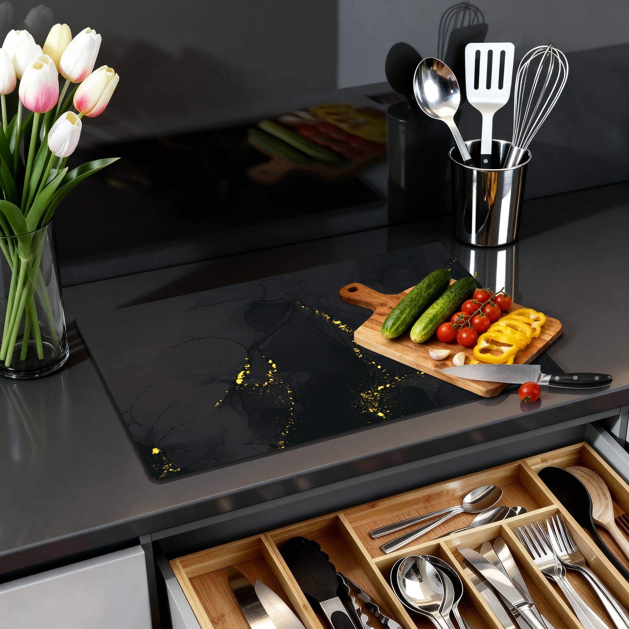 Black Marble Gold - Herdabdeckplatte auf einer modernen Küchenarbeitsplatte mit Gemüse und Utensilien.
