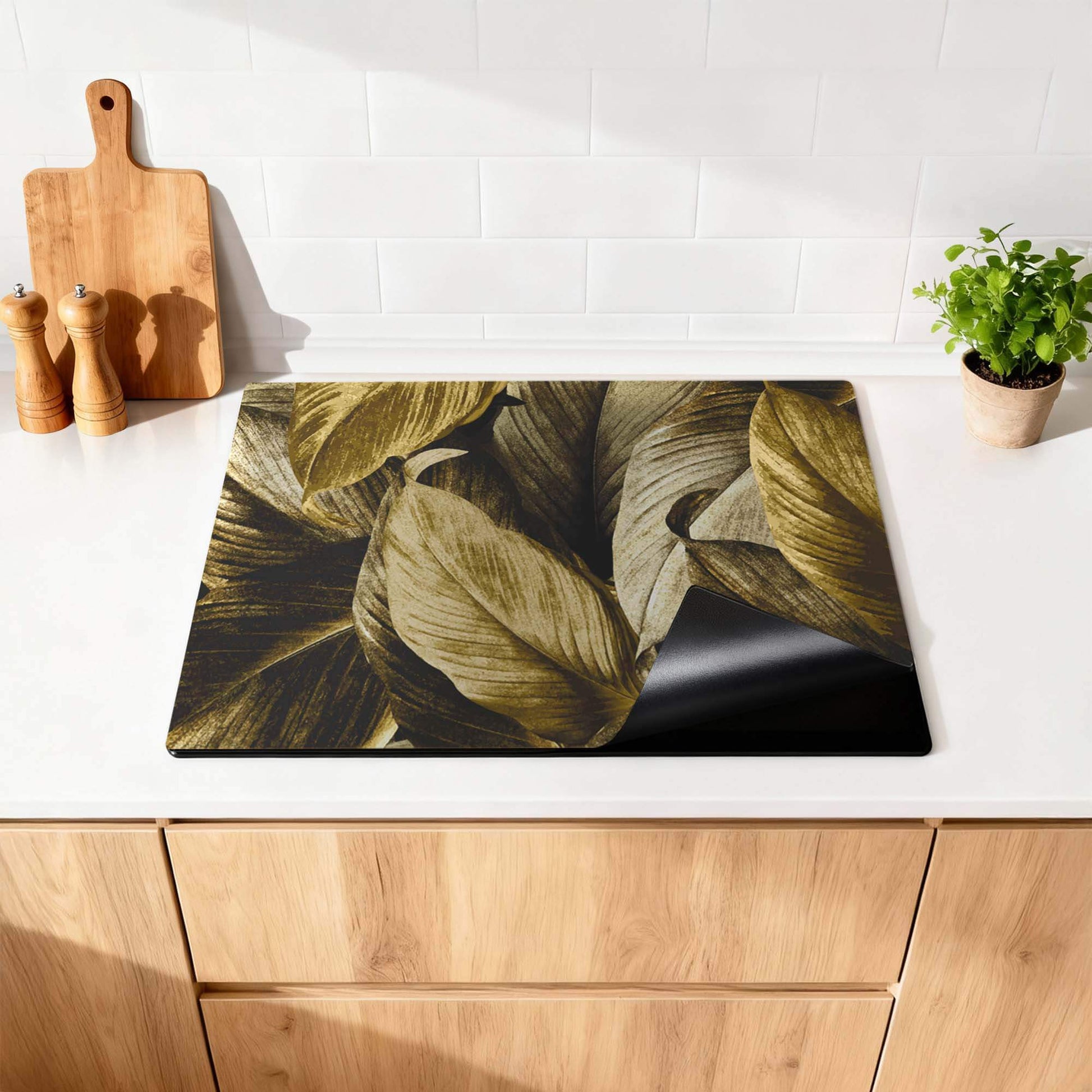 Golden Leaves - Herdabdeckplatte mit botanischem Luxus auf einer Küchenarbeitsplatte.