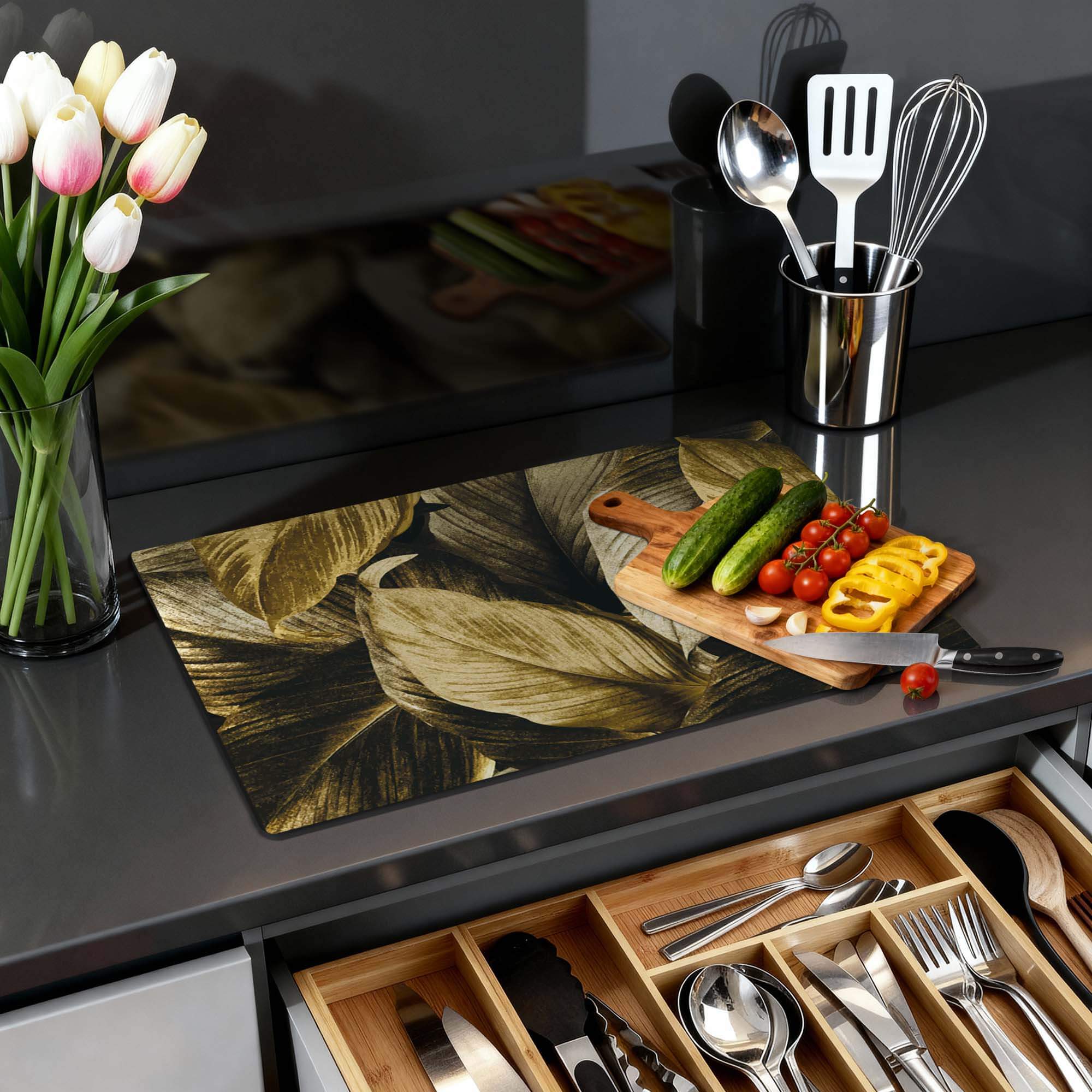 Goldenes Blätterdesign des Golden Leaves - Herdabdeckplatte auf einer modernen Küchenarbeitsplatte mit Gemüse und Utensilien.