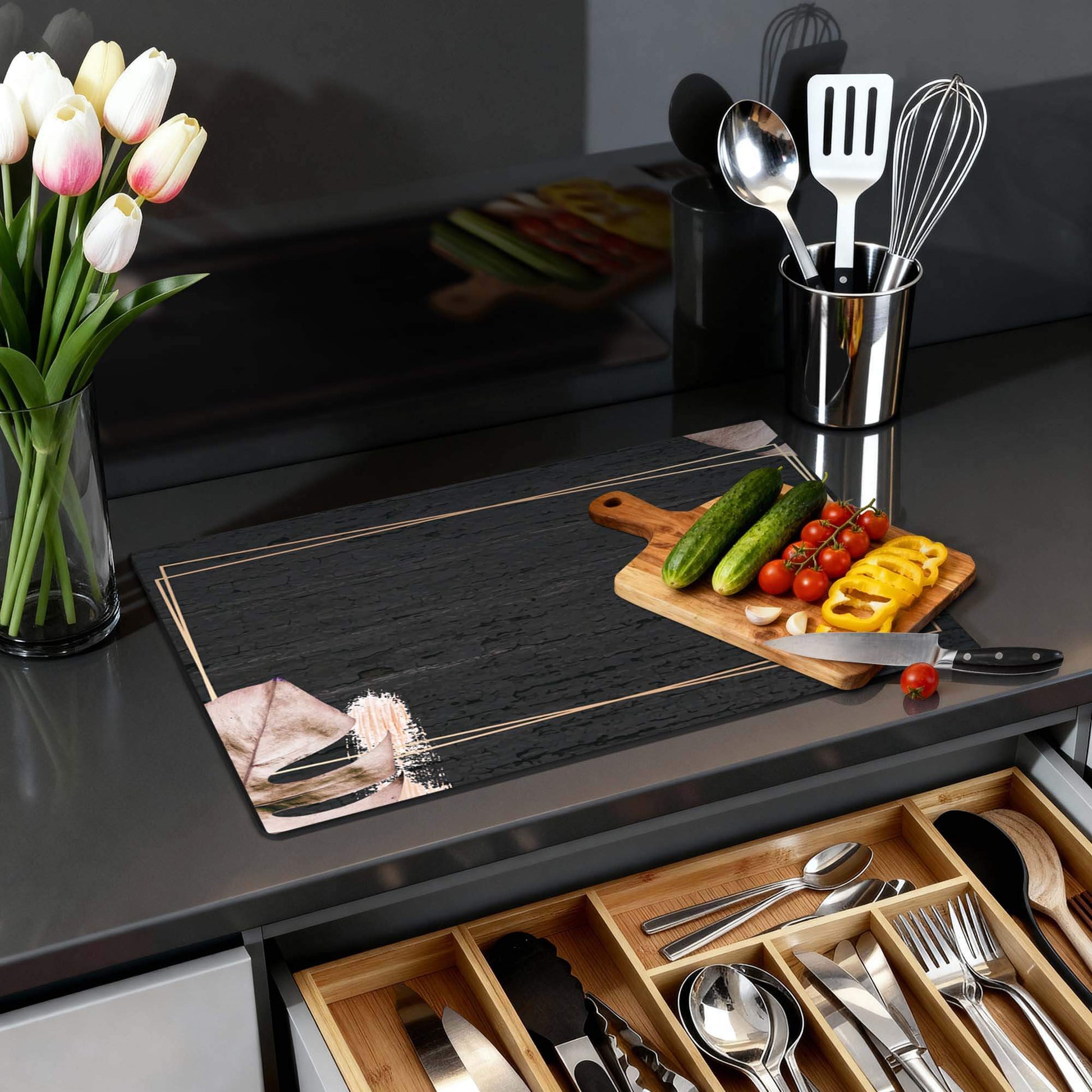 Midnight Leaves - Herdabdeckplatte mit schwarzem Hintergrund und beigen Blättern auf einer modernen Arbeitsplatte.