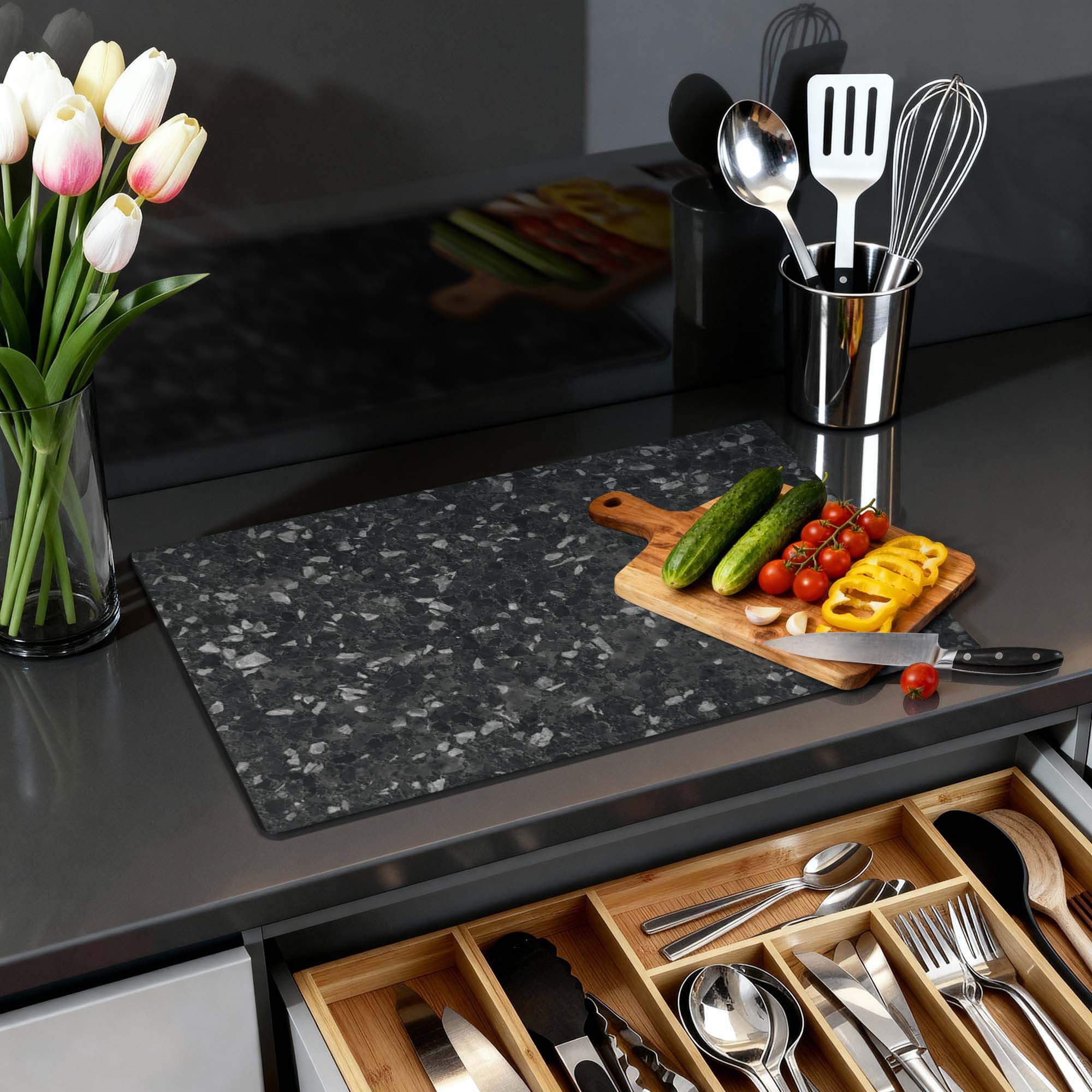 Obsidian Granite - Herdabdeckplatte auf einer Küchenarbeitsplatte mit Gemüse und einer Blumenvase.