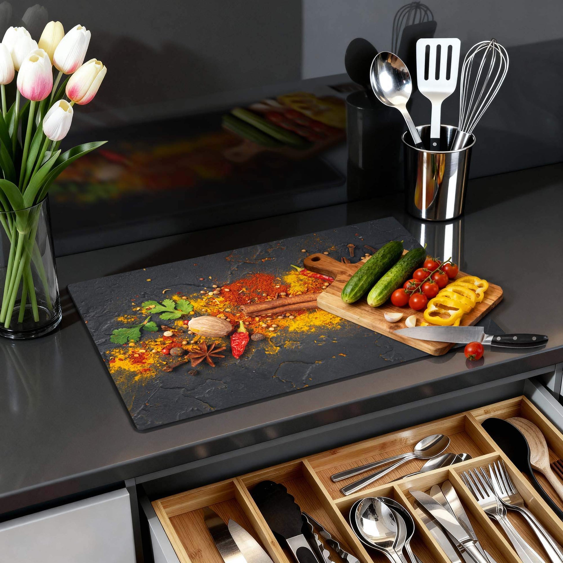 Spice Canvas - Herdabdeckplatte mit buntem Gewürzmotiv auf anthrazitfarbenem Hintergrund in moderner Küche.