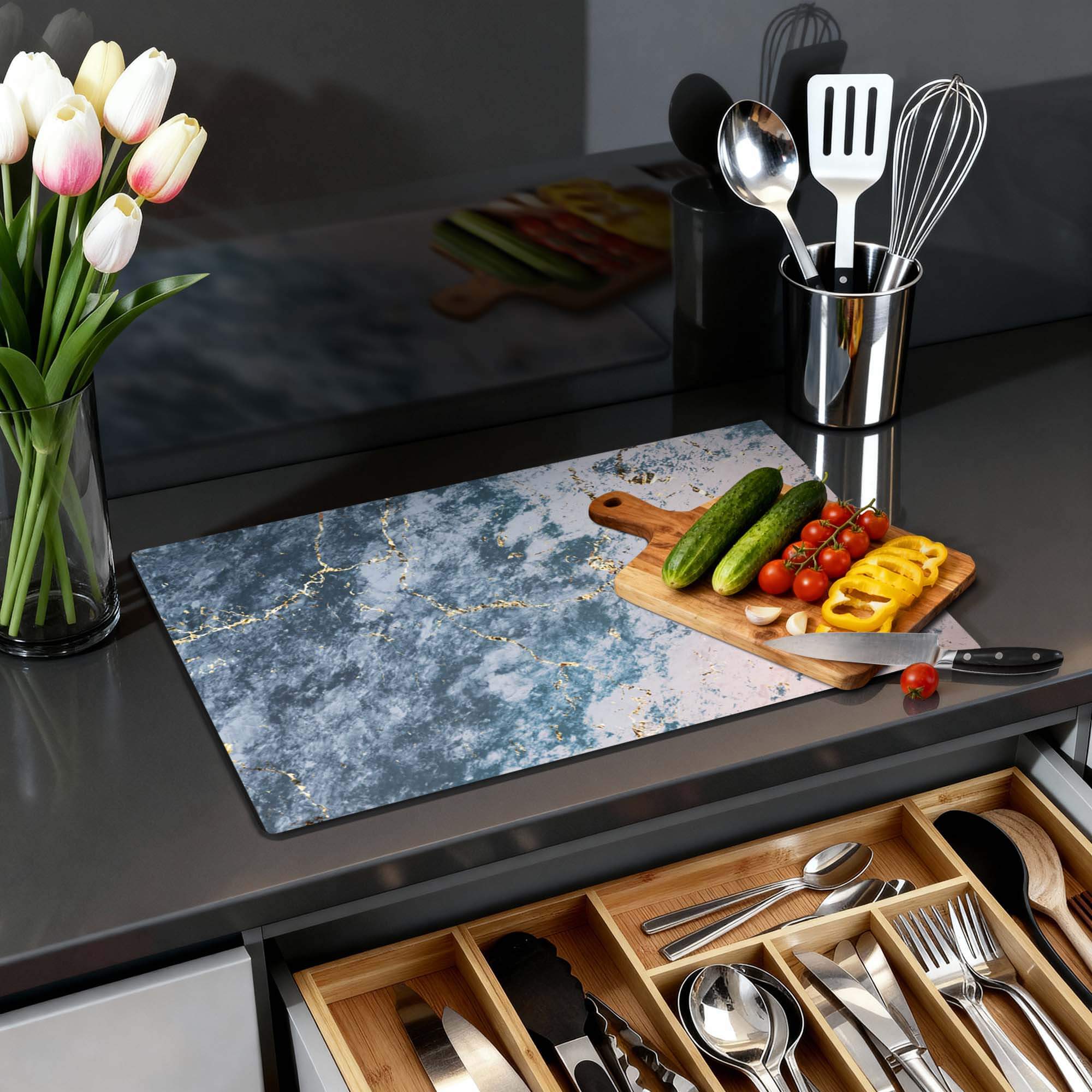 Eleganter Ozeanmarmor - Herdabdeckplatte auf einer Küchenoberfläche mit Gemüse und Blumen.