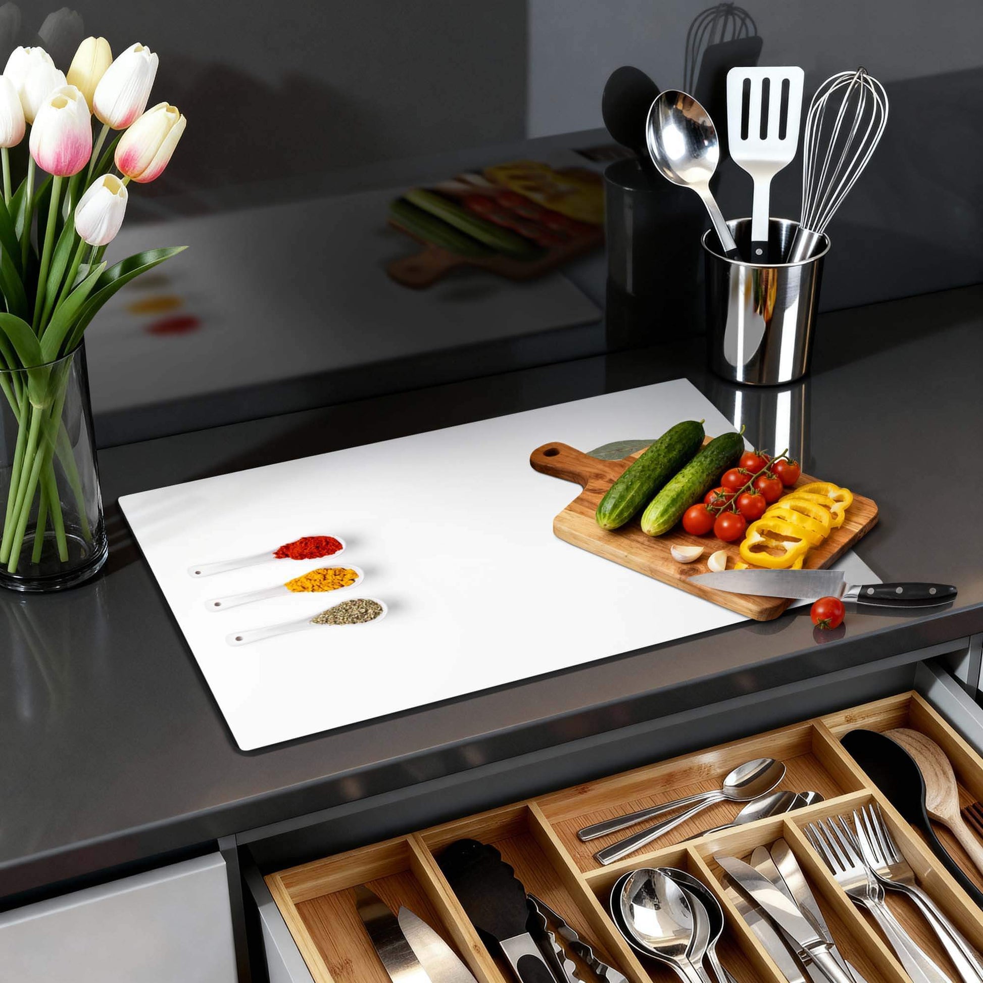 Moderne Küche mit Bay & Blend - Herdabdeckplatte, Schneidebrett, Gemüse und Kräutern auf der Arbeitsplatte.