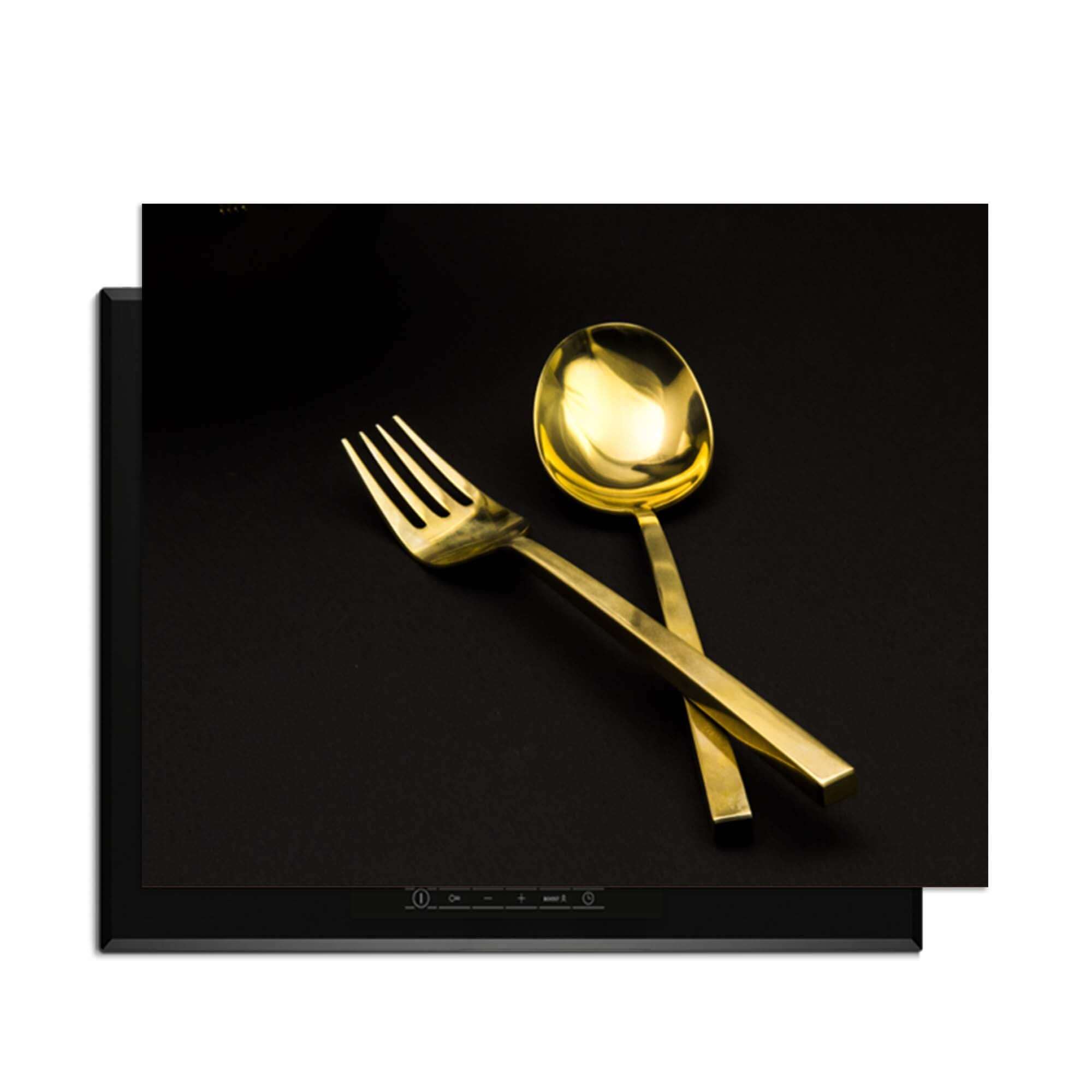 Dining Deluxe - Herdabdeckplatte mit goldenem Besteck auf schwarzem Hintergrund