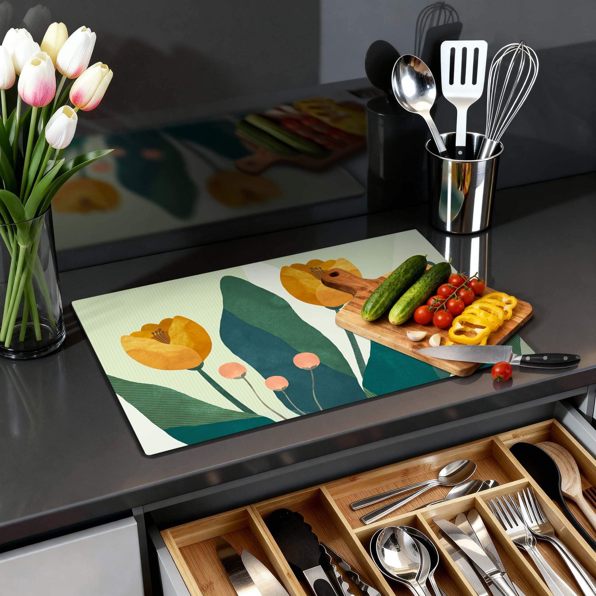 Golden Trio - Herdabdeckplatte mit elegantem botanischem Design auf der Küchenarbeitsplatte mit Gemüse und Utensilien.