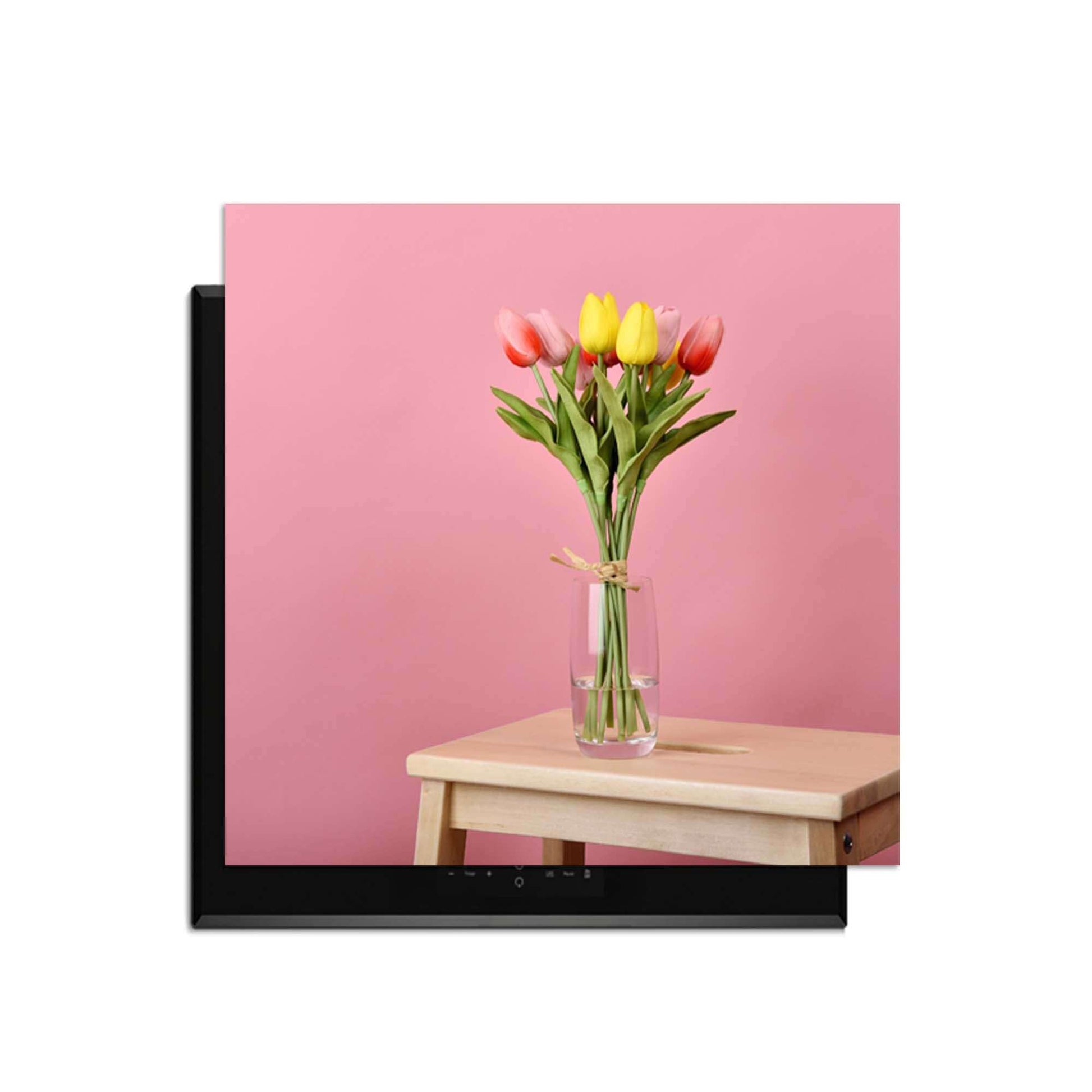 Pastellfarbener Frühling - Induktionswächter mit Blumen auf einem Holztisch vor einem rosa Hintergrund.