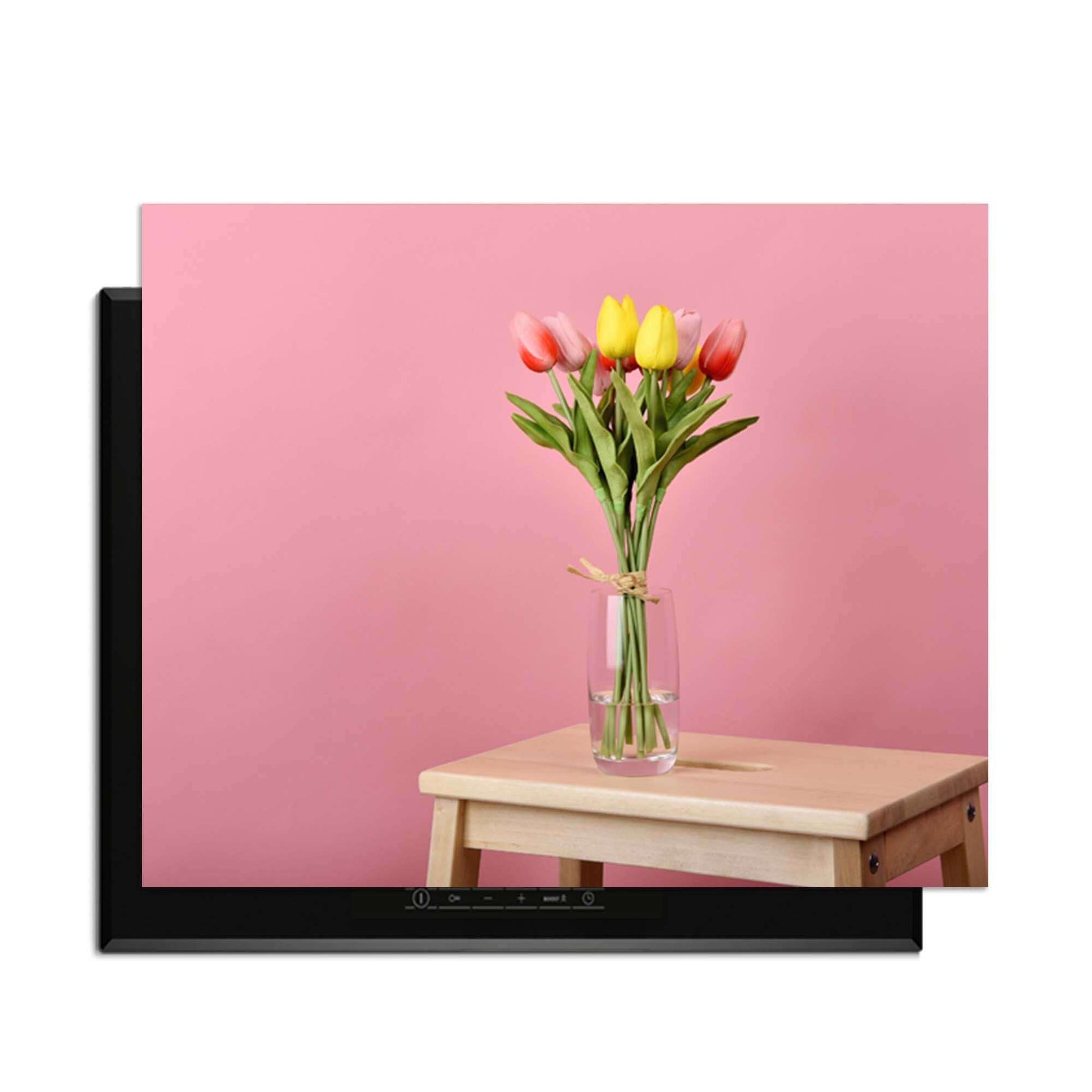 Pastellfarbener Frühling - Induktionswächter mit Blumen auf einem Tisch vor einem rosa Hintergrund.