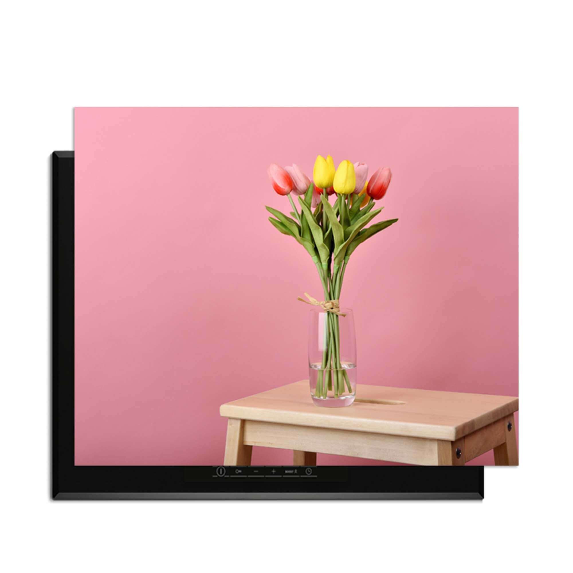 Pastellfarbener Frühling - Induktionswächter mit Blumen auf einem Tisch vor einem rosa Hintergrund.
