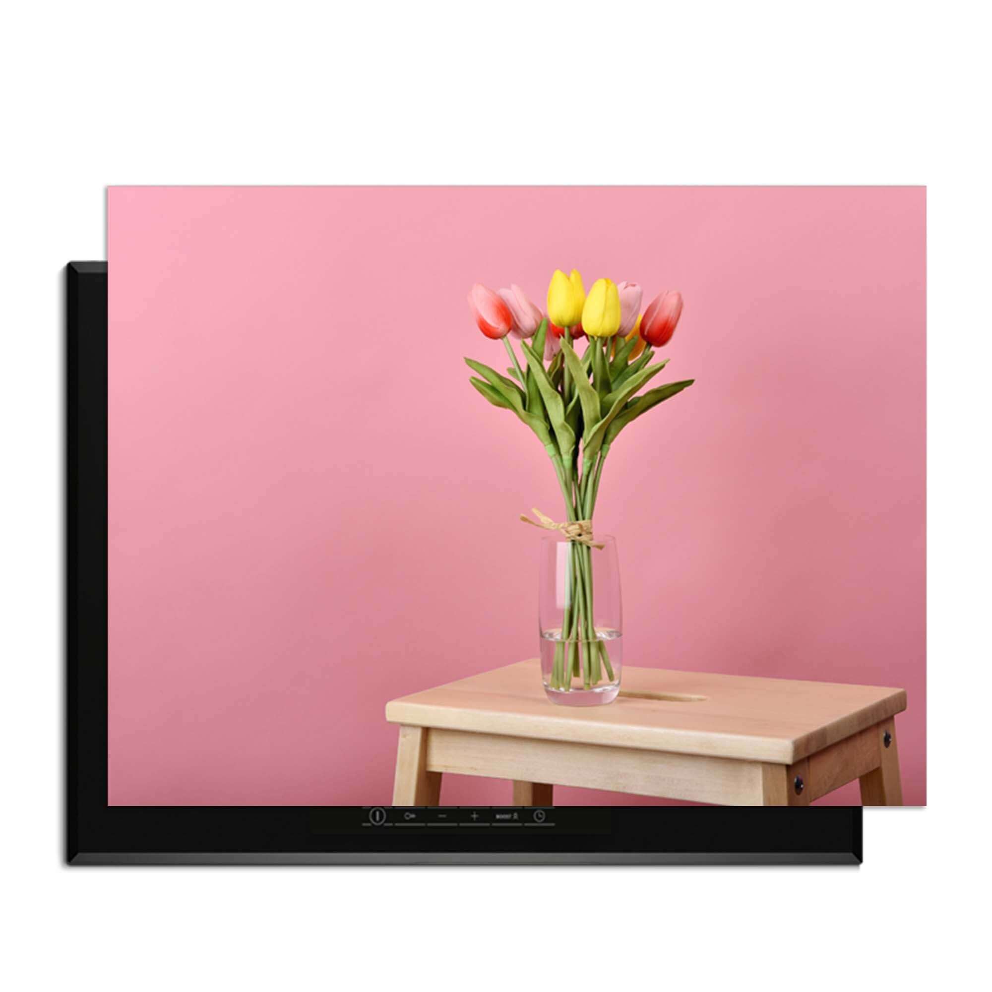 Pastellfarbener Frühling - Induktionswächter mit einem Strauß Tulpen auf einem Holztisch vor einem rosa Hintergrund.
