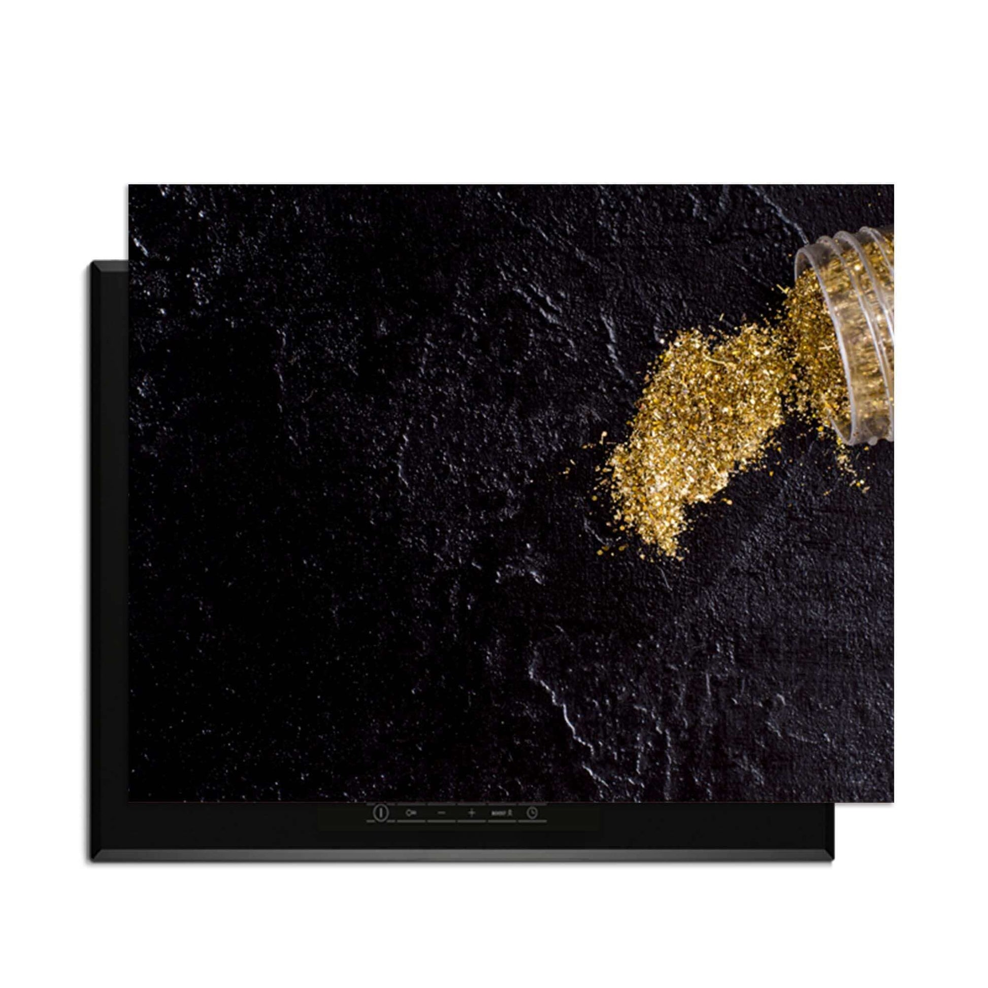 Spilled Gold - Herdabdeckplatte auf schwarzem Hintergrund mit Goldpulver.
