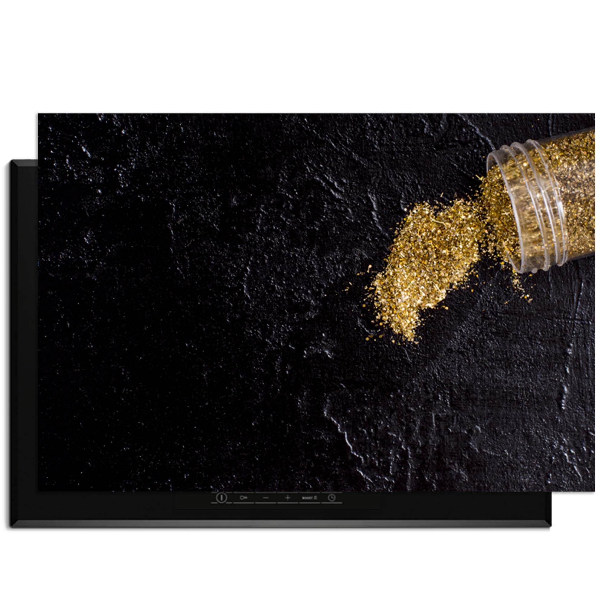 Spilled Gold - Herdabdeckplatte mit goldenem Glitter auf schwarzem Hintergrund.