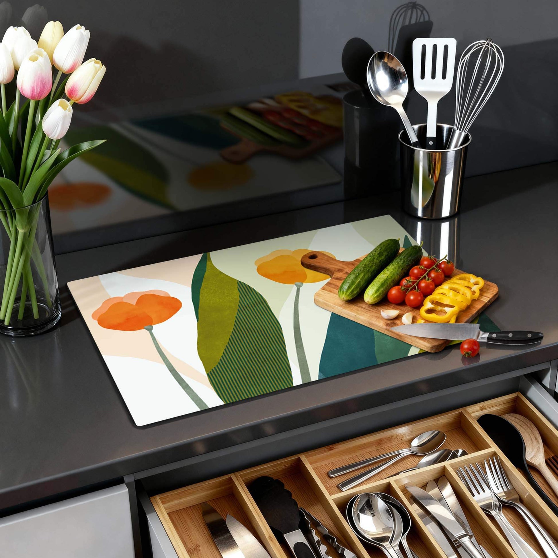 Sunset Blooms - Herdabdeckplatte mit orangefarbenen Blumen und grünen Blättern, Küchenzubehör auf schwarzer Arbeitsplatte mit Gewürzen und Besteckschublade.