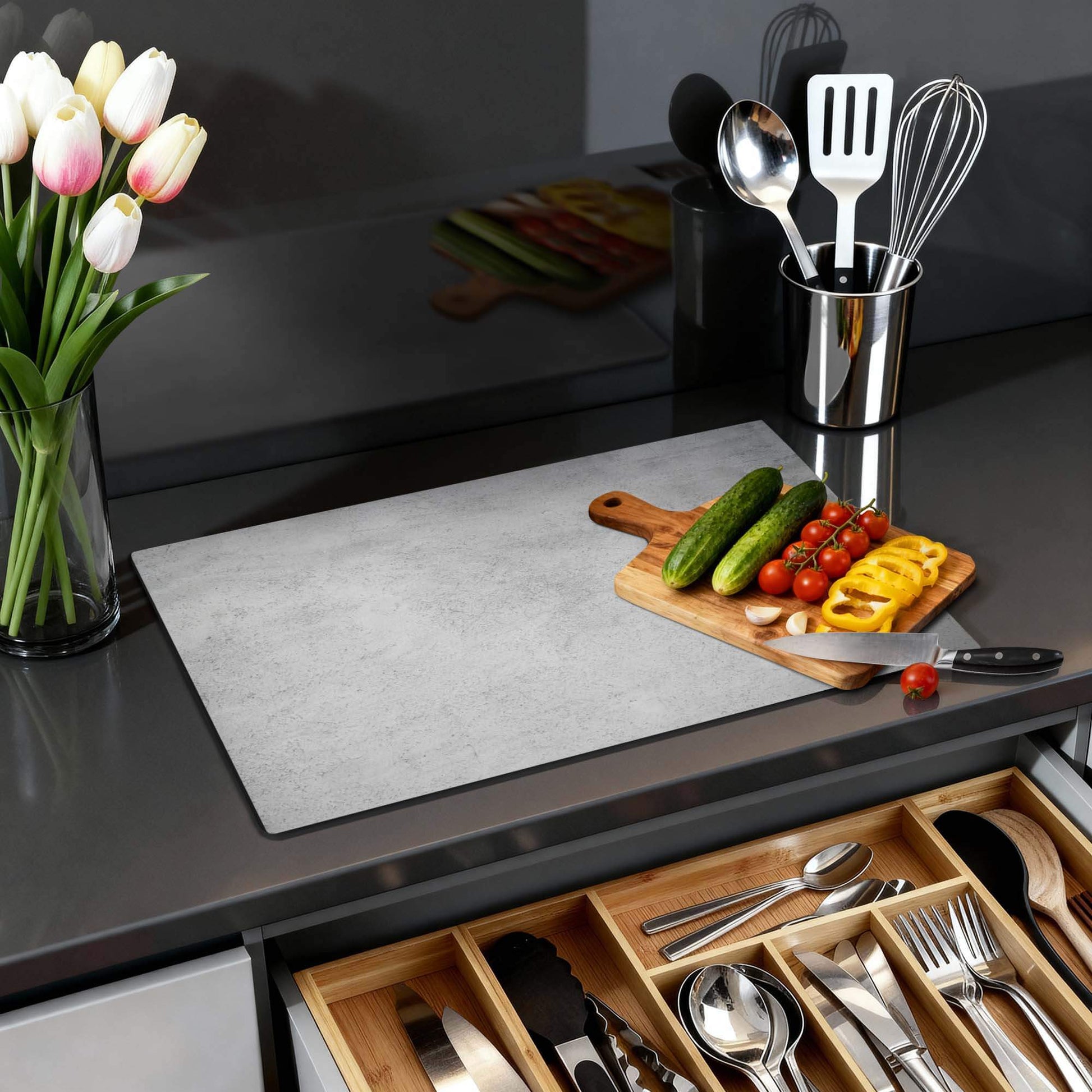 Urban Grey - Herdabdeckplatte auf einem Küchentisch mit Gemüse und Kochutensilien.