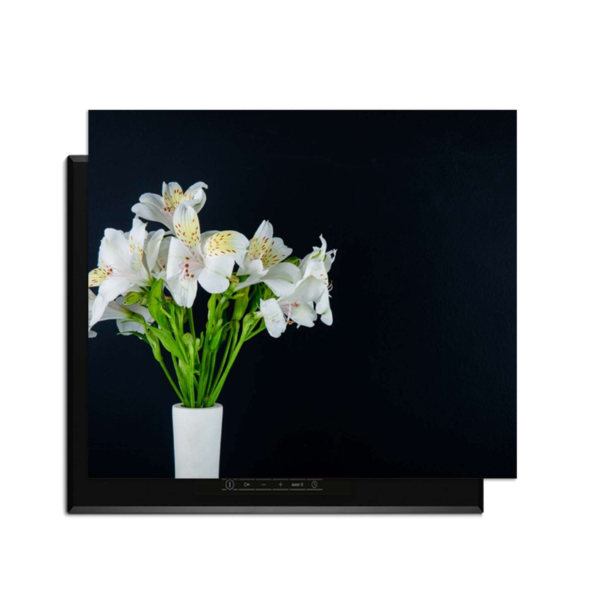 White Whisper - Induktionswächter mit weißen Blumen auf einem Induktionskochfeld mit schwarzem Hintergrund.