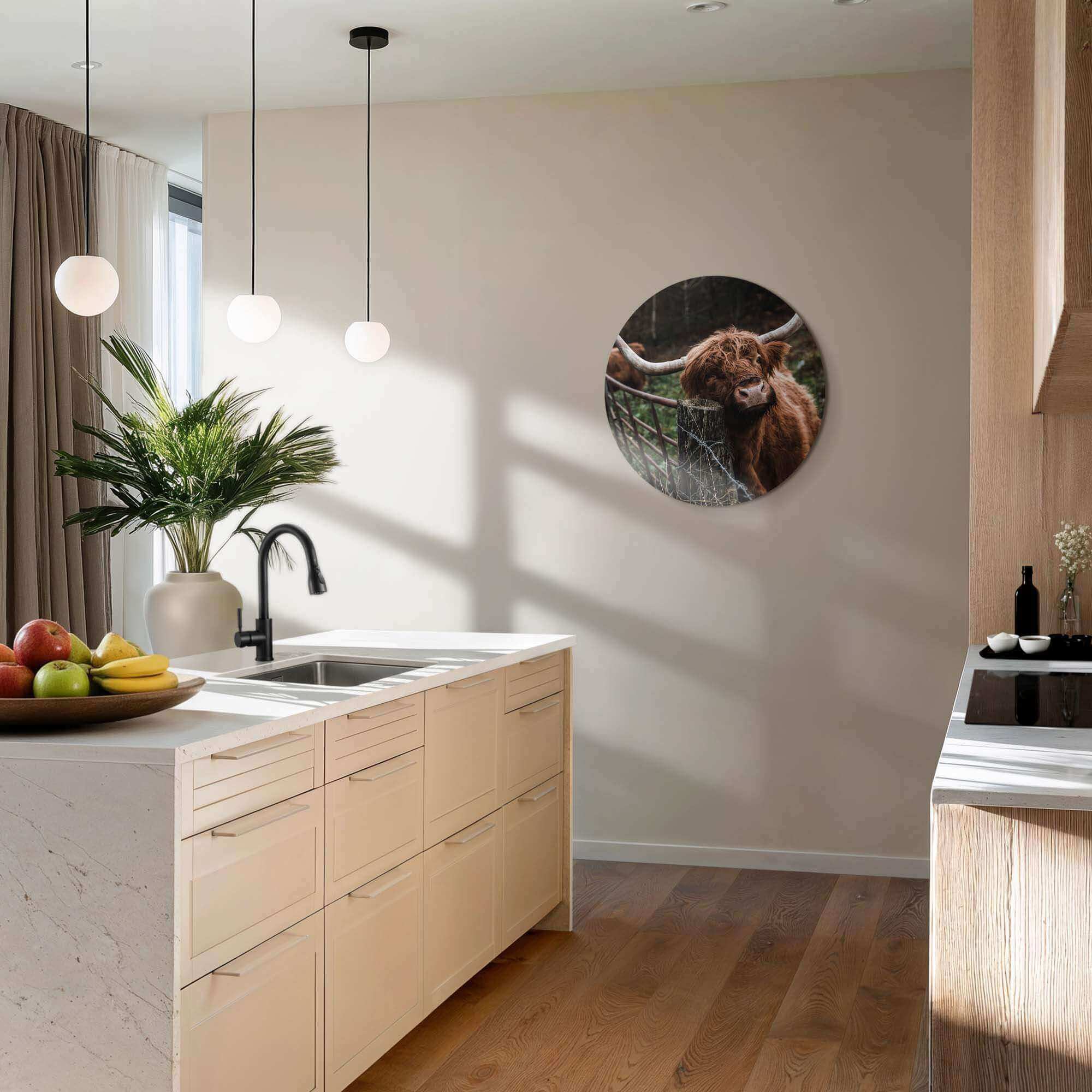 Moderne Kücheneinrichtung mit Holzfußboden, Marmorarbeitsplatten, Hängeleuchten und einem an der Wand befestigten runden Tierkunstwerk.