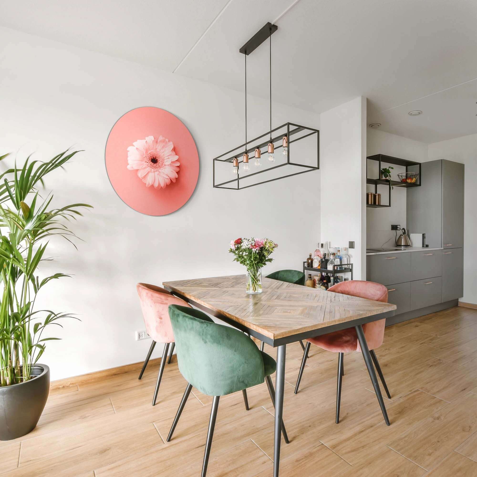 Coral Gerbera - Wandbild auf korallenrosa Hintergrund in einem modernen Esszimmer mit Holztisch.