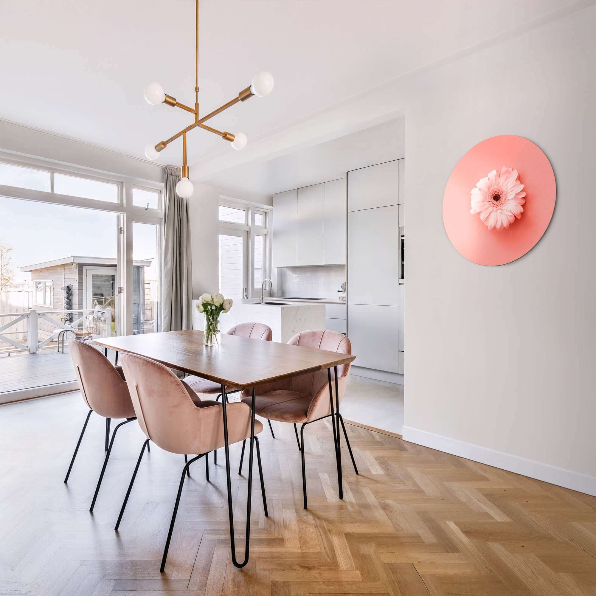 Coral Gerbera - Wandbild an einer Wand in einem modernen Esszimmer mit einem Holztisch und rosa Stühlen.