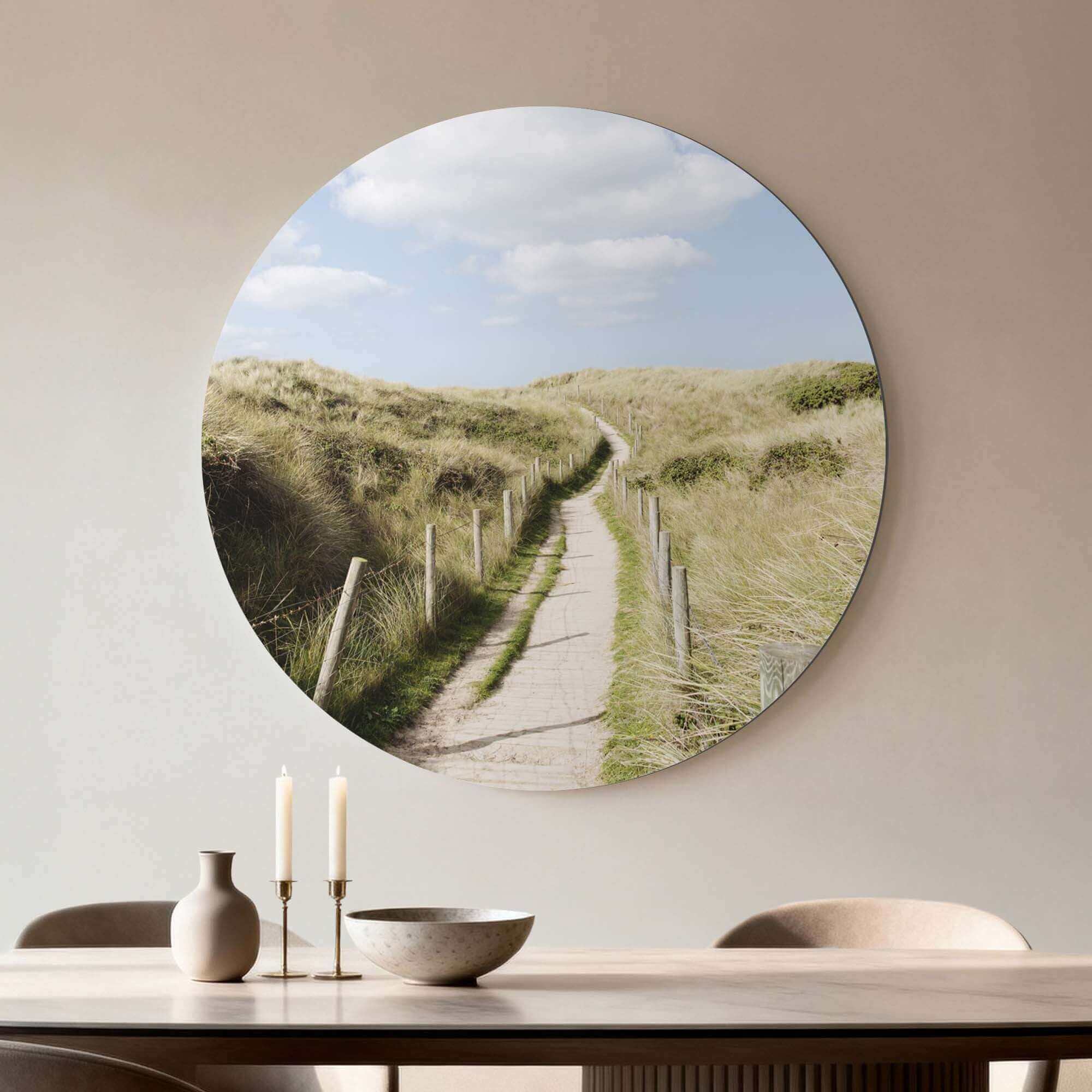 Decorative wall art featuring a scenic path through grassy dunes under a blue sky, styled above a minimalist table setting with candles.