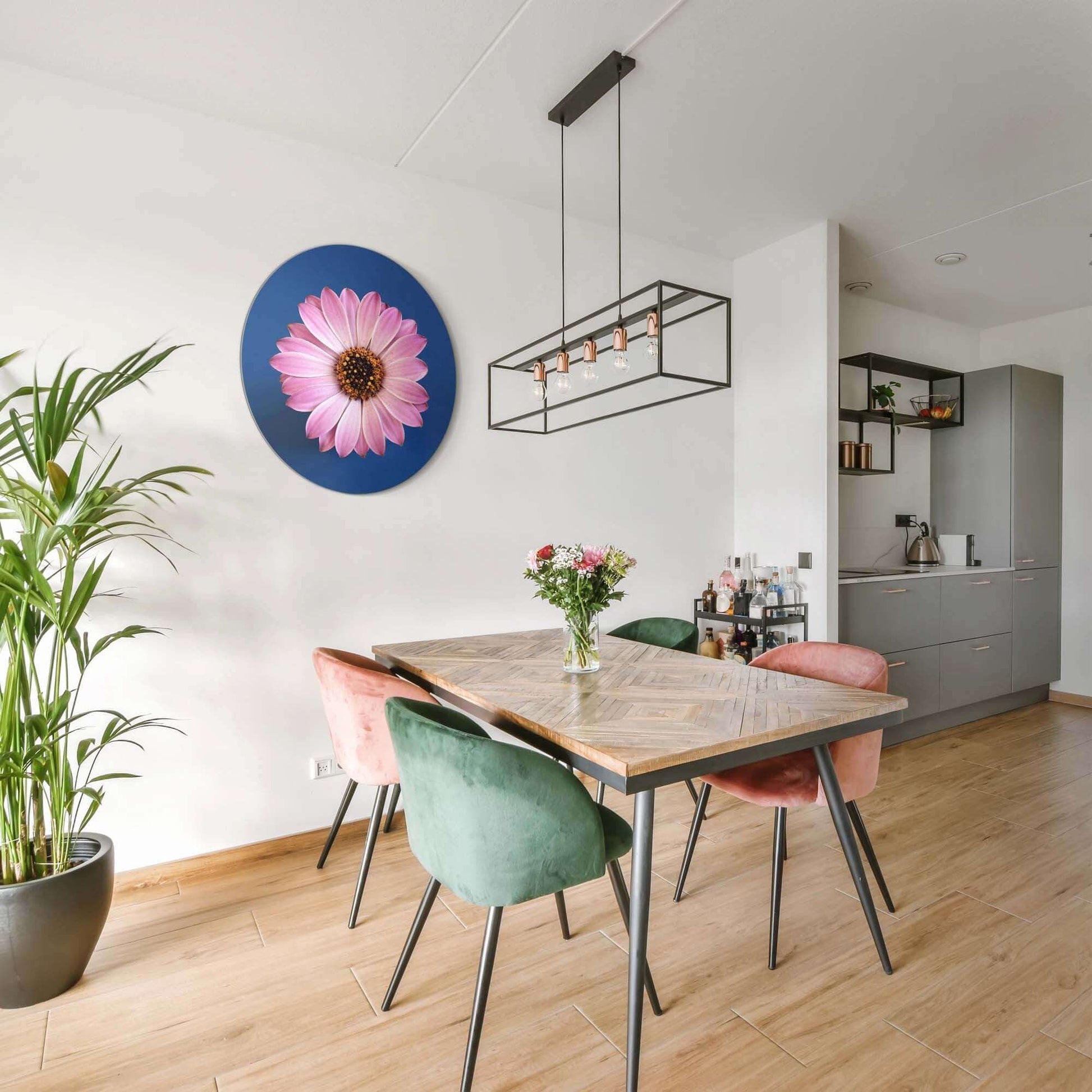 Pastellfarbenes Gänseblümchen - Wandbild an einer Wand in einem modernen Esszimmer mit Holztisch und Stühlen.