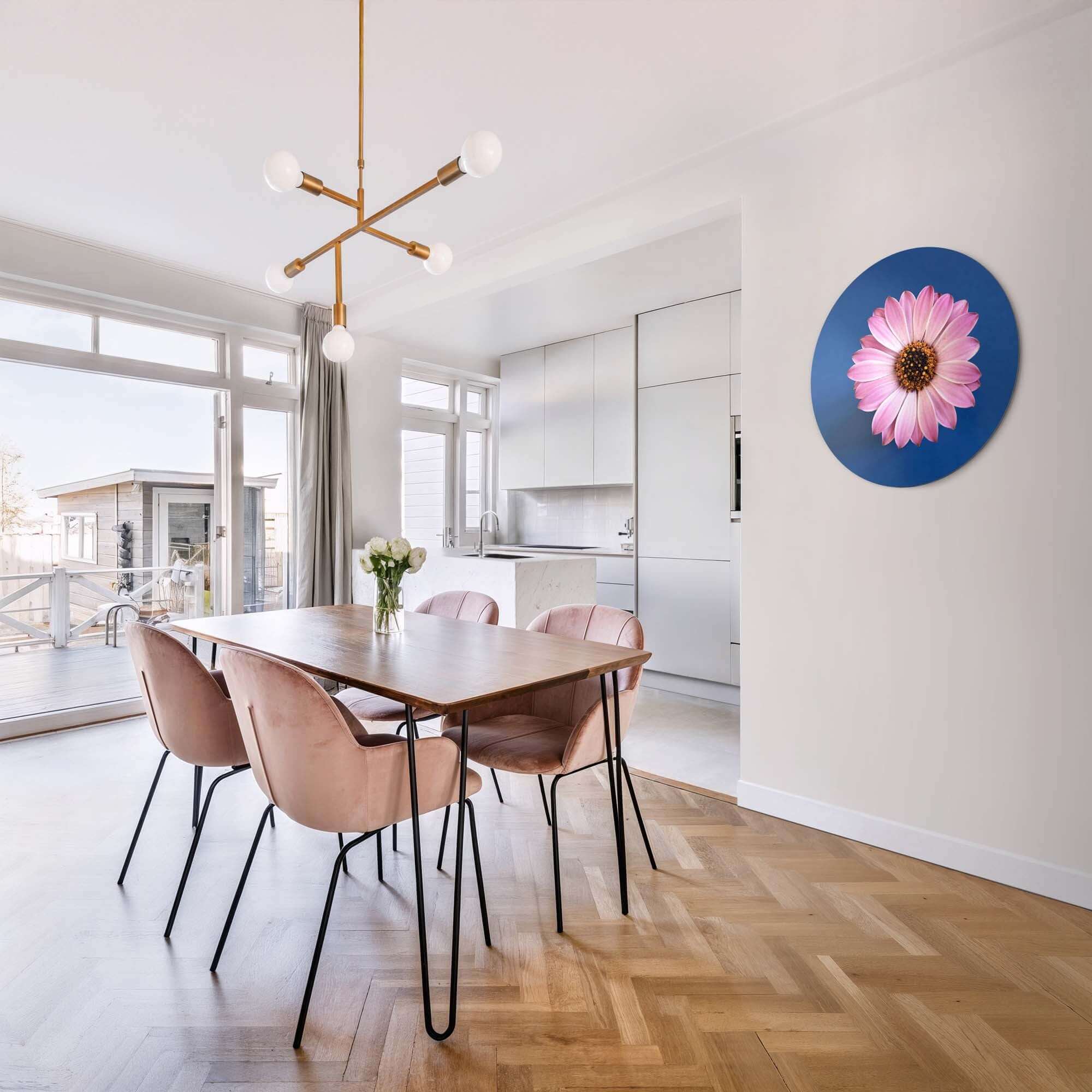 Pastellfarbenes Gänseblümchen - Wandbild an der Wand über einem Tisch in einem modernen Interieur mit rosa Stühlen.