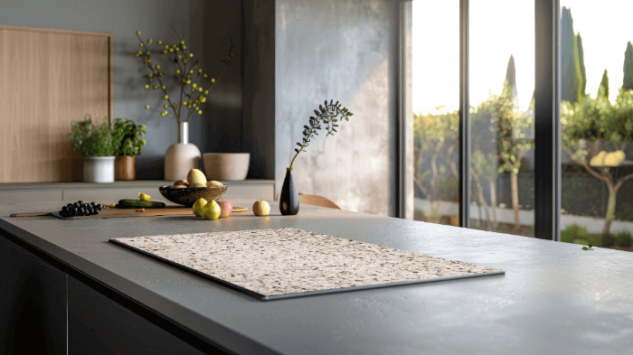 Stilvoller Induktionswächter in Mandelgranitoptik auf einer modernen Kücheninsel mit natürlichem Licht